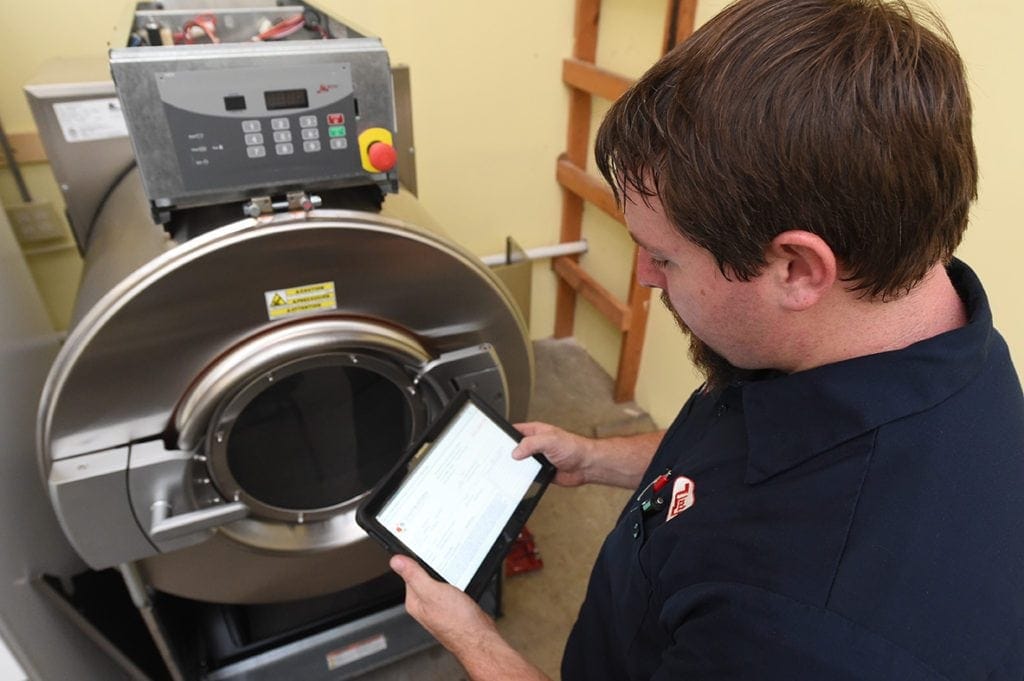Technician conducting scheduled maintenance on a industrial washer.