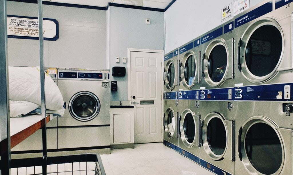 A laundromat with rows of silver washing machines and a white door