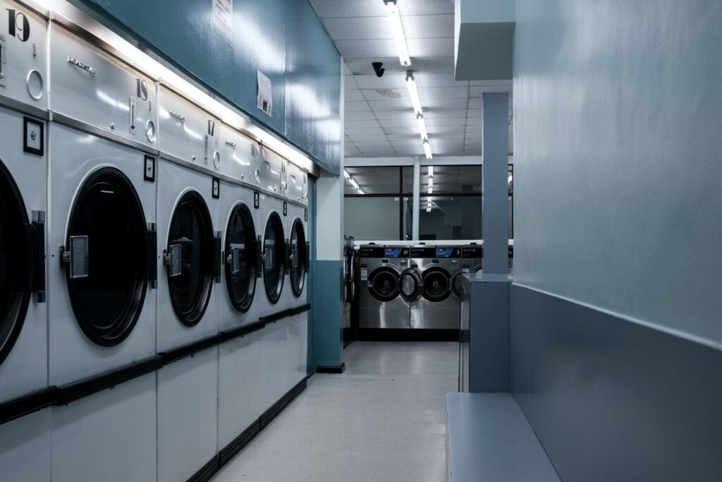 A laundromat with rows of washers in a cool-toned, lit room