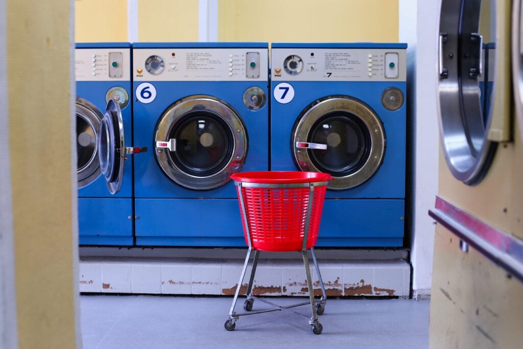 Row of blue washing machines with a red laundry basket in foreground