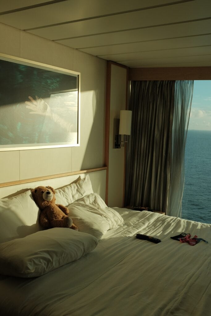 Teddy bear on made bed in a room with an ocean view