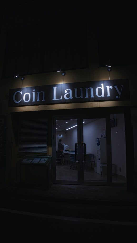 Night view of a Coin Laundry storefront with person visible inside