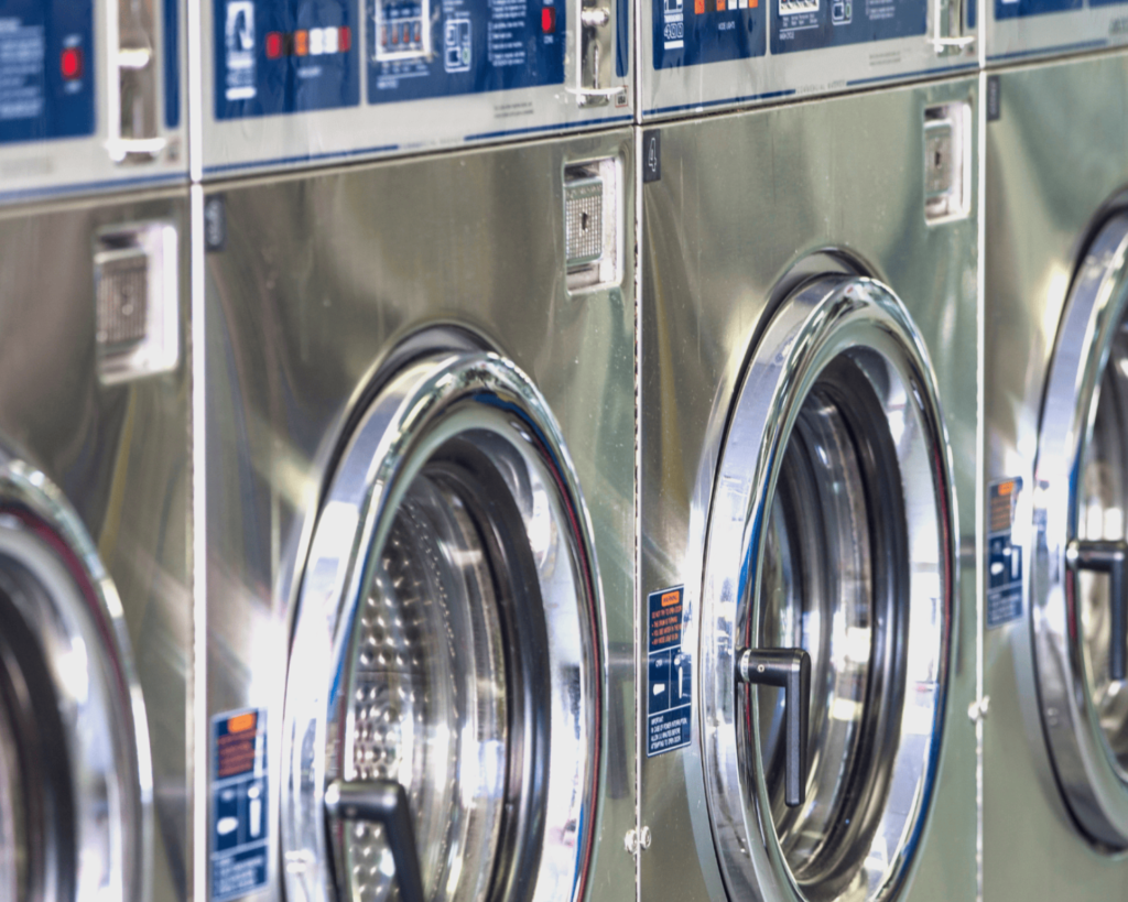 Stainless-steel coin-op washing machines inside a Bessemer laundry room.