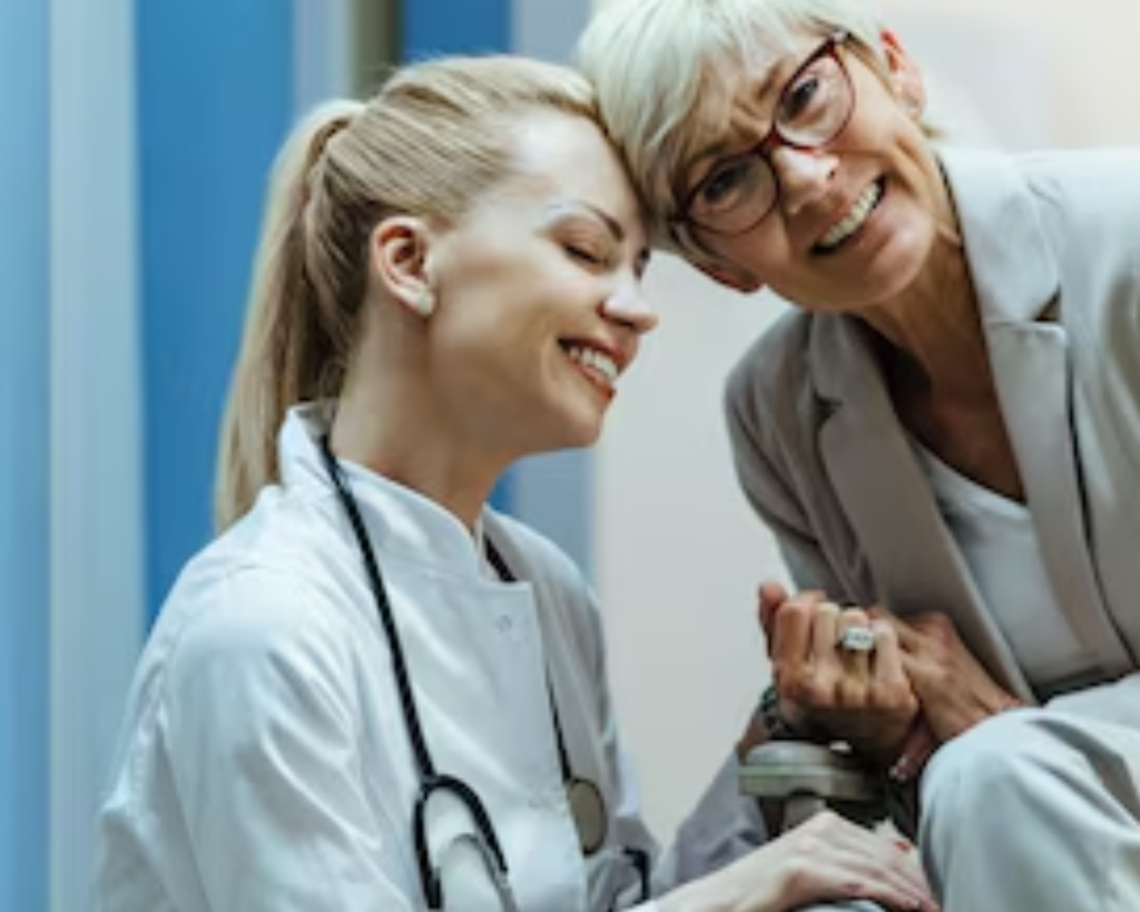 Healthcare professional smiling while speaking with an older woman in a clinical care setting
