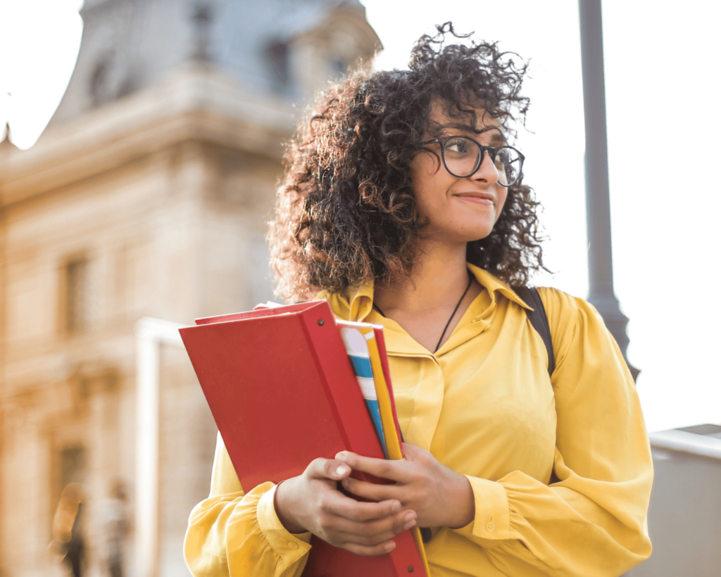 Student holding folders on a sunny day at a Murfreesboro university.