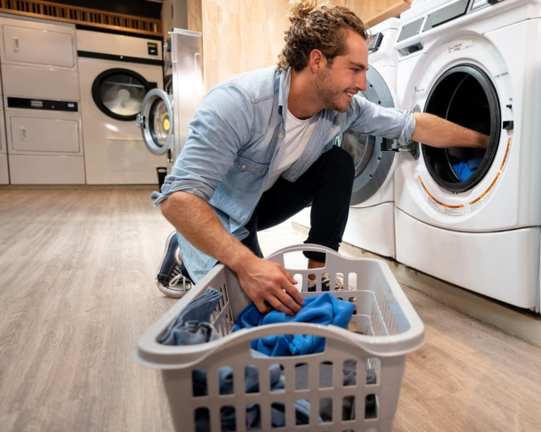 Man loading clothes into a coin-operated washer at a Homewood laundromat.