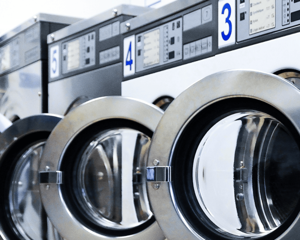 Commercial front-load washers lined up in a Millbrook laundromat.