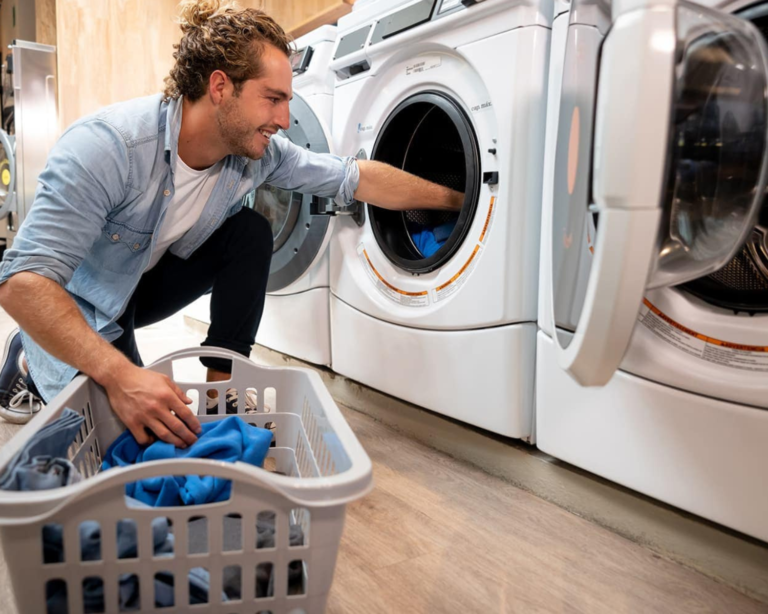 Resident loading laundry into a shared coin-operated washer in a Murfreesboro condo laundry room with modern front-load machines.