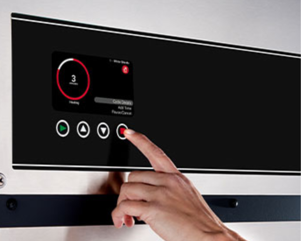 User pressing a button on a digital commercial washer interface in a Millbrook laundry room.