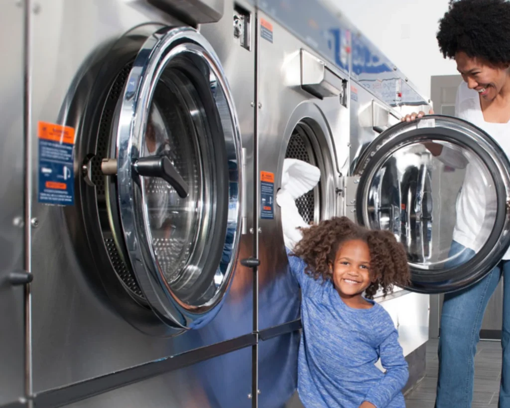 Family using commercial washers in a clean laundromat, showing how convenience and add-ons can increase laundromat revenue per visit