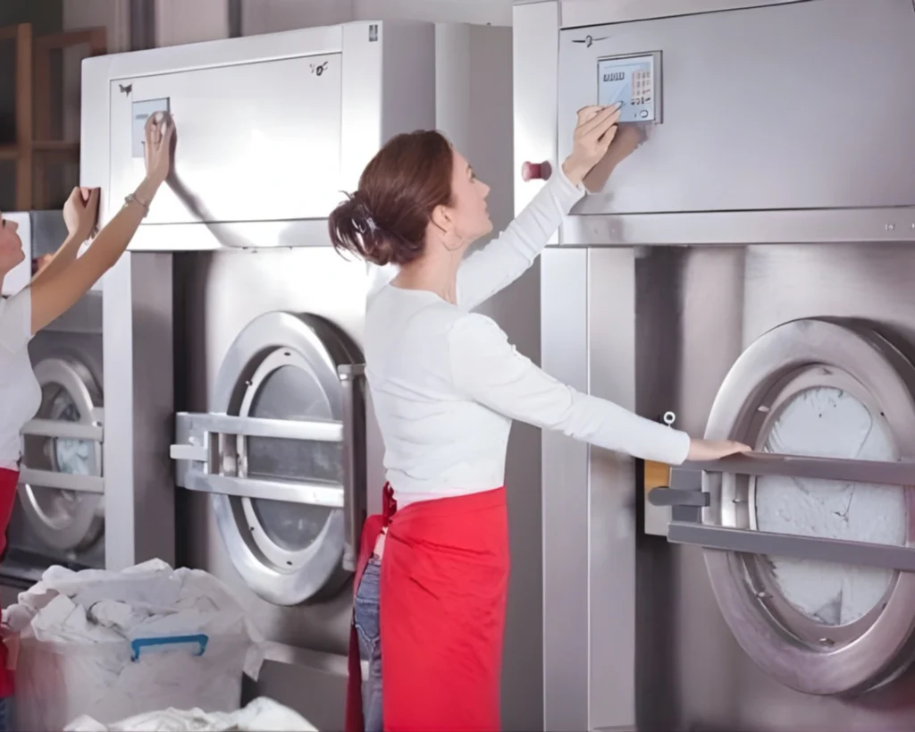 Hotel staff member operating commercial front-load washers supplied by Southeastern Laundry for Richmond Hill hospitality properties.
