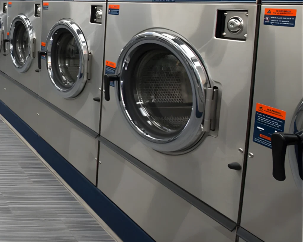 Row of stainless steel front-load commercial washers installed for Columbus laundromat operations by SELaundry.