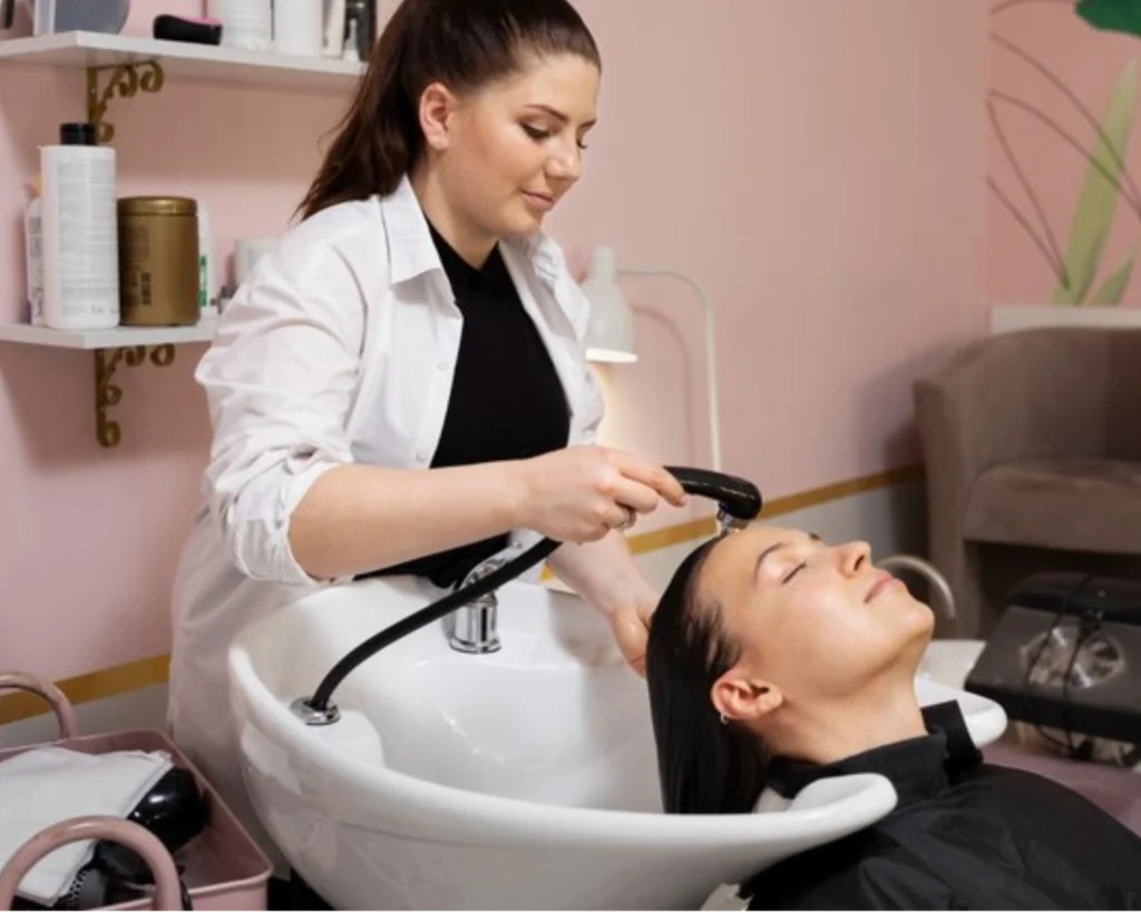 Salon worker washing a client’s hair, representing commercial washer repair support for salon operations in Conway, SC.