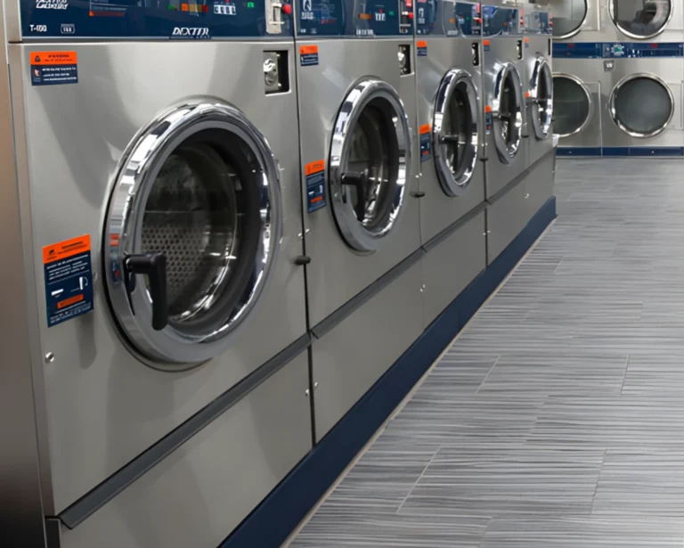 Row of coin-operated commercial washers installed in a shared laundry room for multifamily housing in Prattville, AL.
