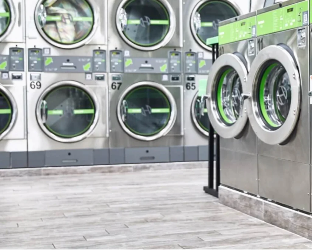 High-capacity Huebsch commercial washers arranged in a modern laundromat layout with multiple units.