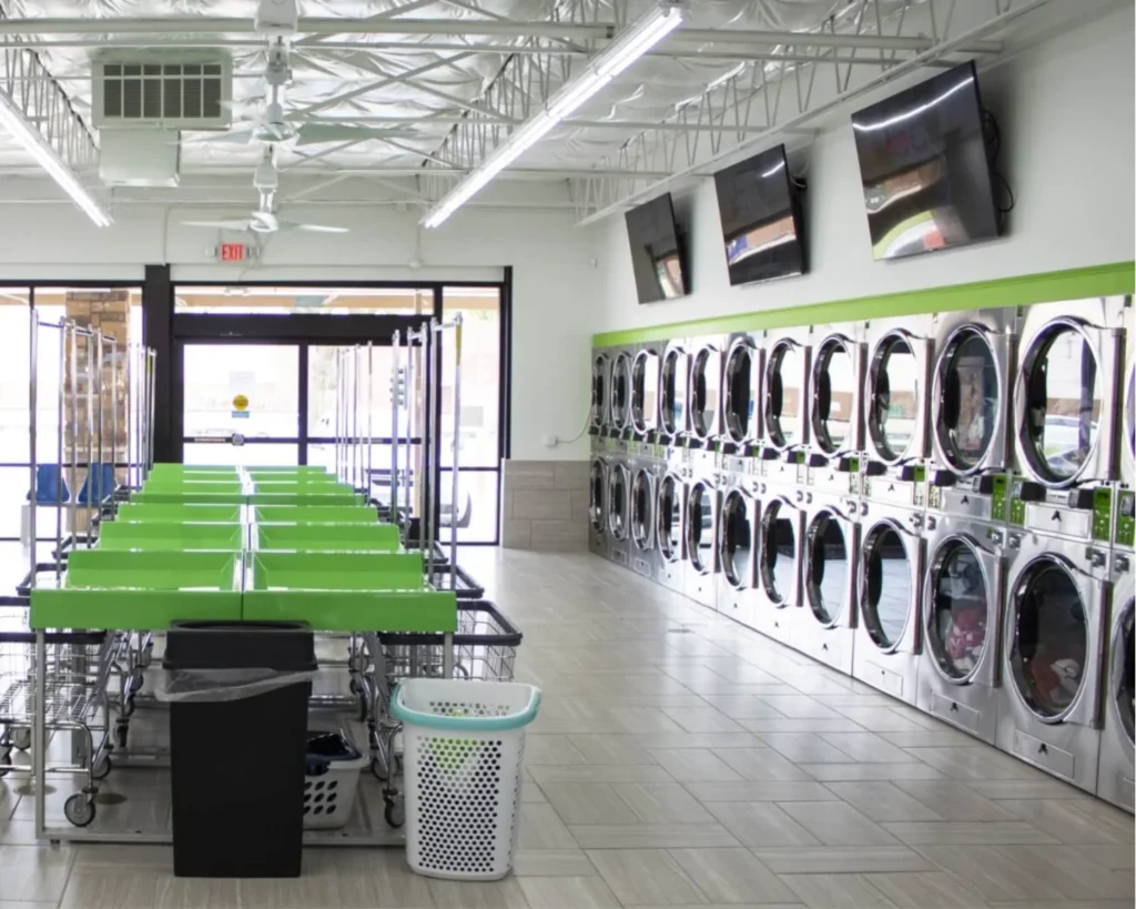 Spacious laundromat interior with Huebsch equipment, folding tables, and organized customer workflow areas.