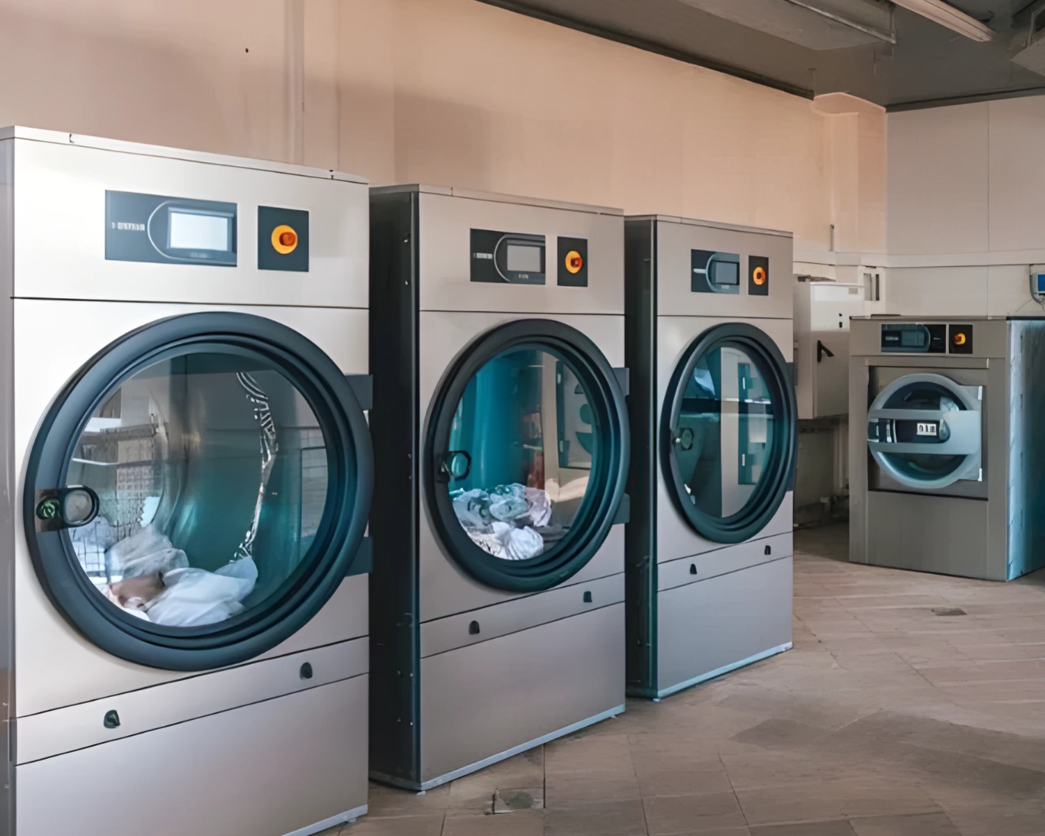 Row of large-capacity commercial washer and dryer for sale in Orlando operating in a clean laundry room, processing linens for high-volume use.
