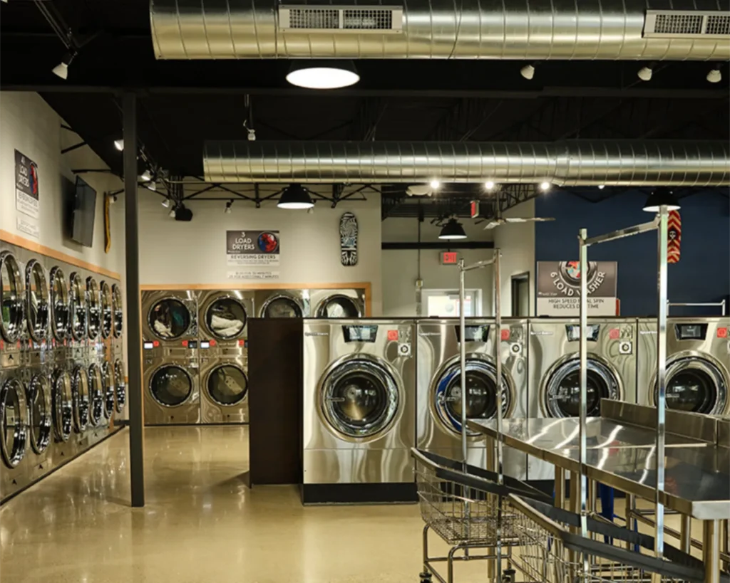 Orlando laundry room with Speed Queen® coin operated washer units, stacked dryers, rolling carts, and folding tables.