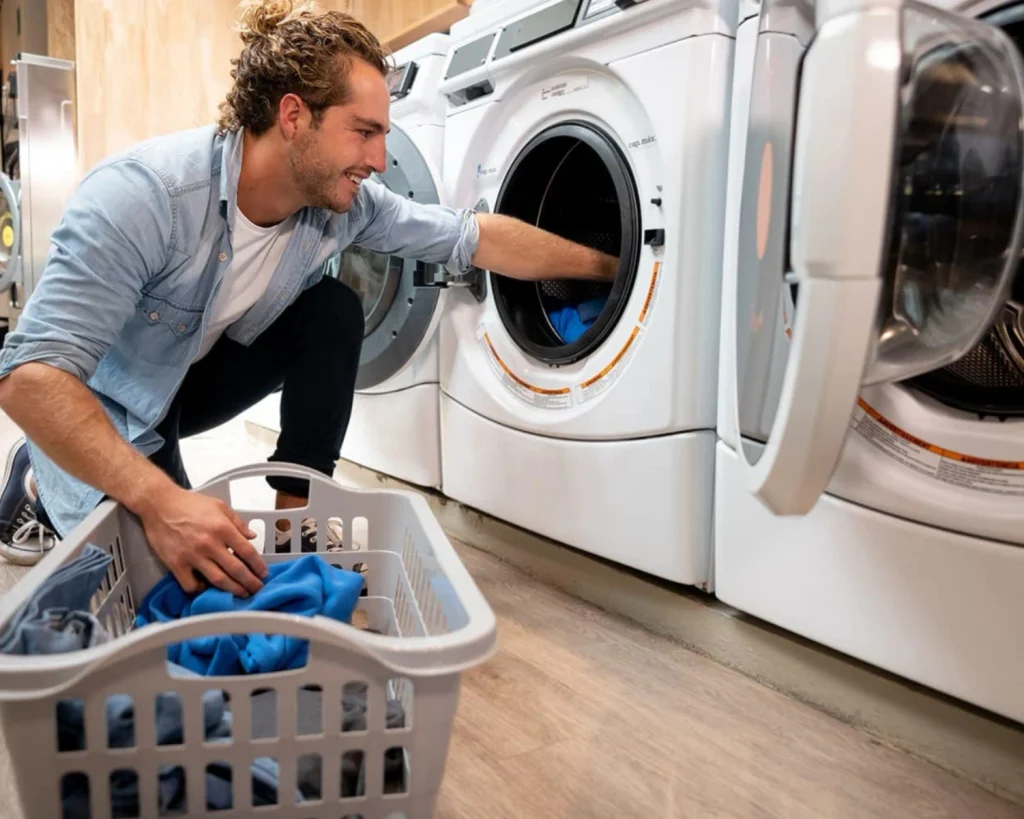 Resident using commercial washers in a multi-family laundry room with a modern laundry payment system.