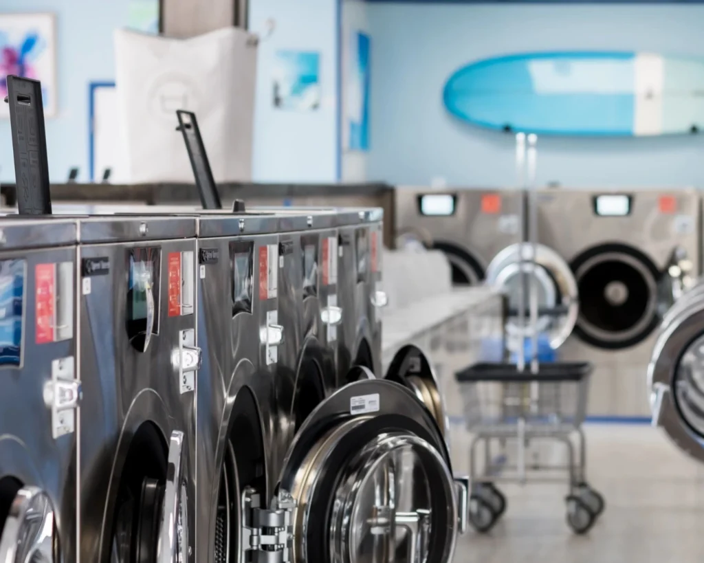 Rows of commercial washers and laundry carts in a clean store set up to prevent laundromat equipment damage.